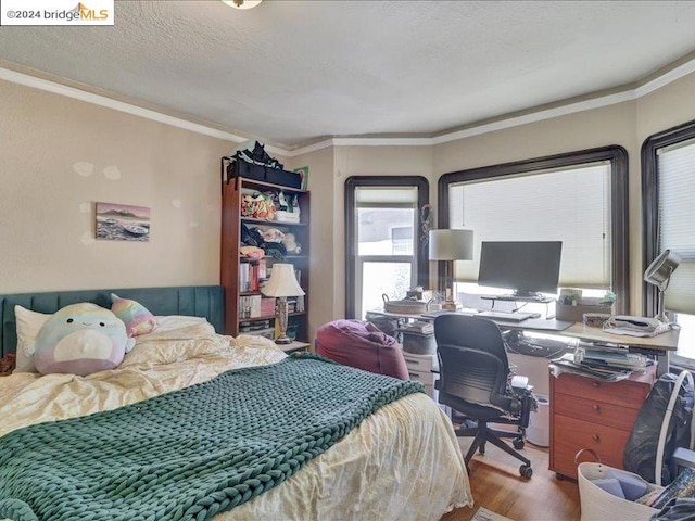 bedroom with ornamental molding, a textured ceiling, and hardwood / wood-style floors