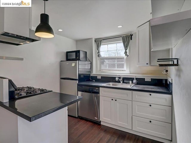 kitchen with sink, appliances with stainless steel finishes, pendant lighting, and white cabinetry