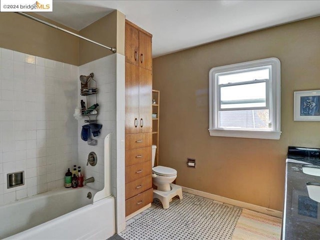 bathroom featuring toilet, tiled shower / bath combo, and tile patterned floors