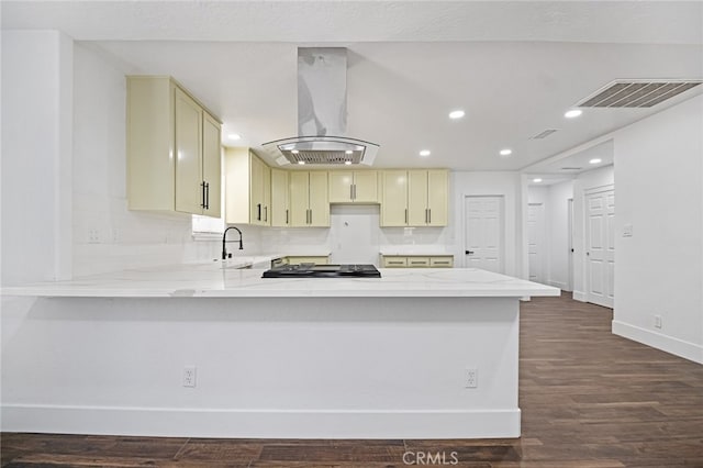 kitchen with kitchen peninsula, island exhaust hood, light stone counters, and dark hardwood / wood-style flooring