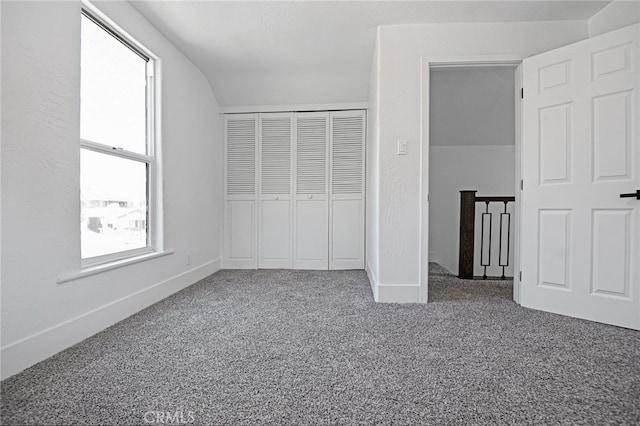 unfurnished bedroom with a closet, lofted ceiling, and carpet floors