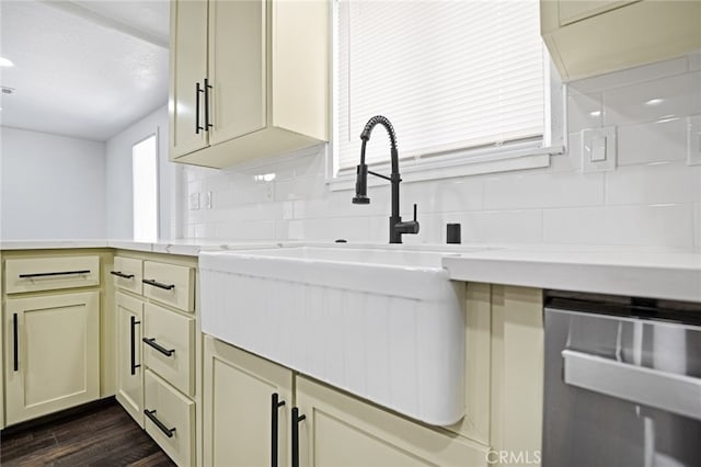 kitchen featuring tasteful backsplash, cream cabinets, stainless steel dishwasher, and dark hardwood / wood-style floors