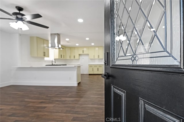 kitchen featuring ceiling fan, wall chimney exhaust hood, dark hardwood / wood-style flooring, and cream cabinets