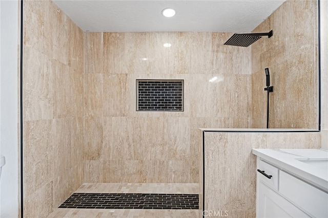 bathroom featuring vanity, a textured ceiling, tiled shower, and tile walls