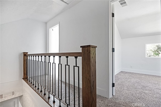 hall featuring vaulted ceiling, a textured ceiling, and carpet floors