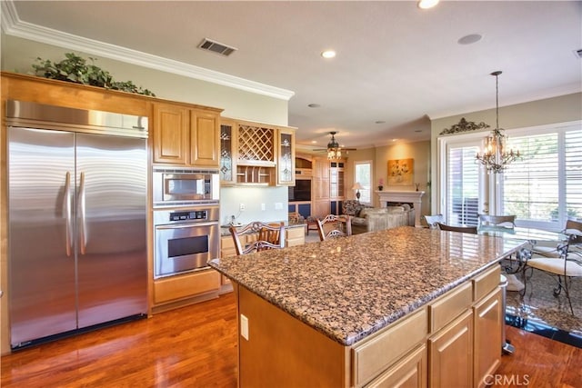 kitchen featuring built in appliances, a center island, dark hardwood / wood-style flooring, and ornamental molding