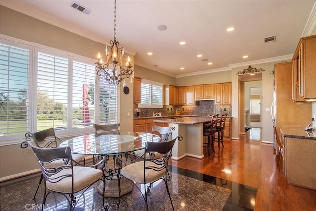 dining room featuring a notable chandelier, crown molding, dark wood-type flooring, and a wealth of natural light