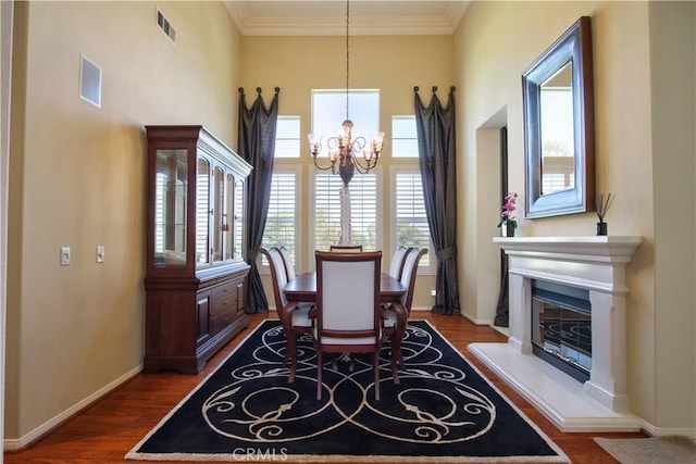 dining space with hardwood / wood-style flooring, ornamental molding, and an inviting chandelier