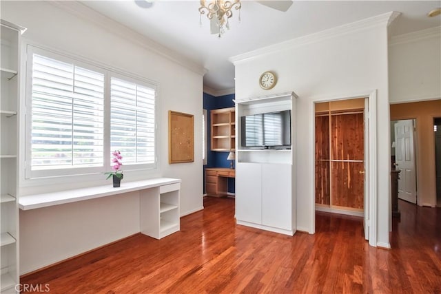 unfurnished office featuring wood-type flooring, built in desk, and crown molding