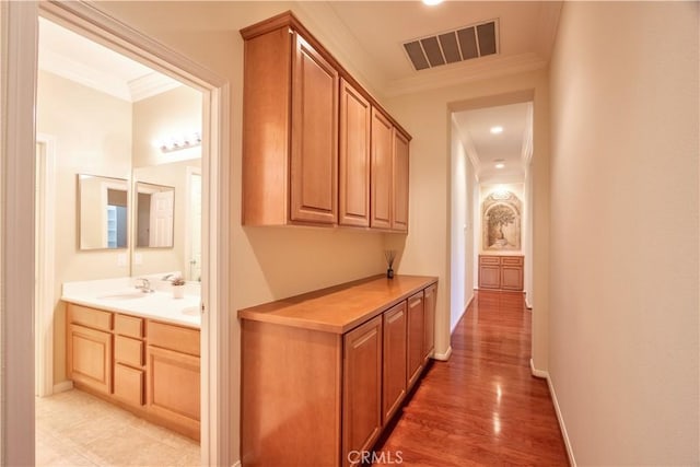 hallway featuring hardwood / wood-style floors, crown molding, and sink