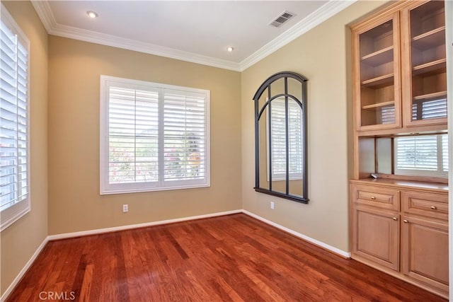 empty room with dark hardwood / wood-style flooring, a healthy amount of sunlight, and ornamental molding