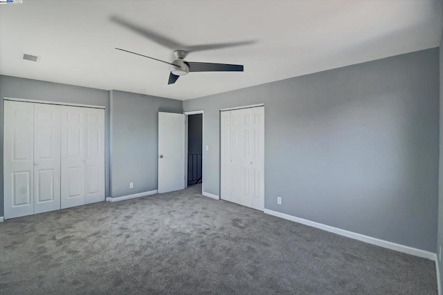 unfurnished bedroom featuring ceiling fan, multiple closets, and carpet floors