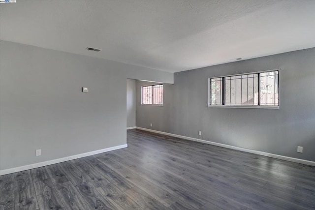 unfurnished room with dark wood-type flooring and a wealth of natural light