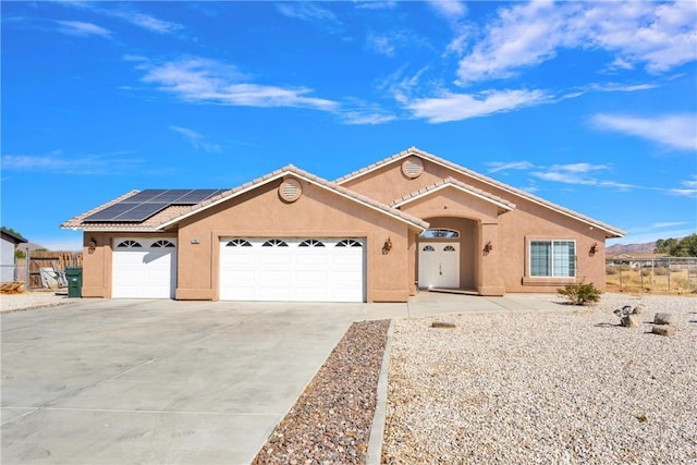 ranch-style home with a garage and solar panels