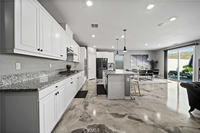 kitchen with white cabinets, an island with sink, a kitchen breakfast bar, decorative light fixtures, and stainless steel appliances