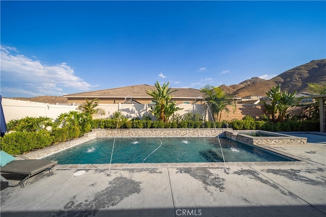 view of swimming pool with an in ground hot tub, pool water feature, a mountain view, and a patio