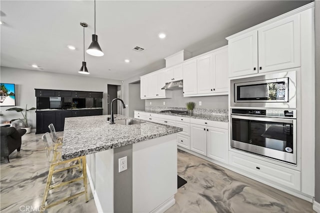 kitchen featuring white cabinets, stainless steel appliances, and light stone counters