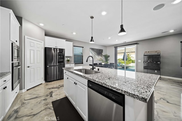 kitchen with white cabinets, a center island with sink, appliances with stainless steel finishes, decorative light fixtures, and sink