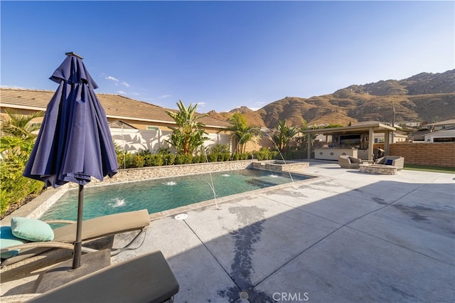 view of swimming pool featuring a mountain view, pool water feature, and a patio area