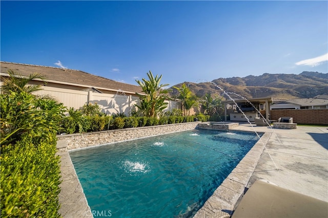 view of pool featuring an in ground hot tub, pool water feature, a mountain view, and a patio