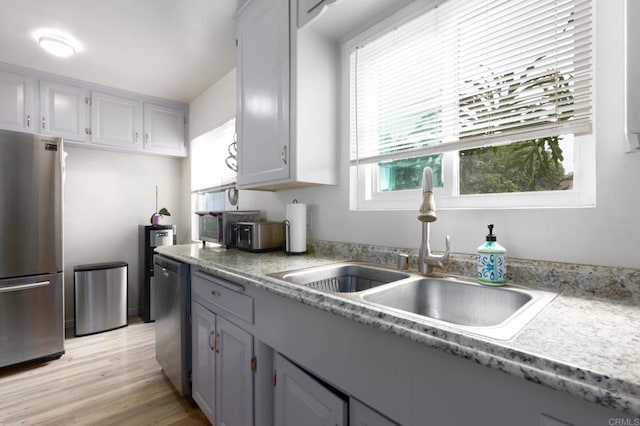 kitchen featuring appliances with stainless steel finishes, light hardwood / wood-style floors, and sink