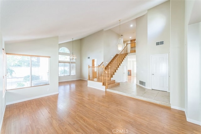 unfurnished room featuring high vaulted ceiling, a chandelier, and light wood-type flooring