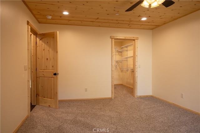 unfurnished bedroom featuring a walk in closet, carpet floors, a closet, ceiling fan, and wooden ceiling