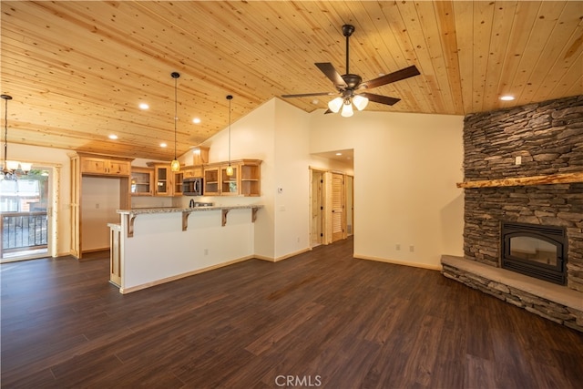 kitchen featuring a stone fireplace, a breakfast bar, decorative light fixtures, and wooden ceiling