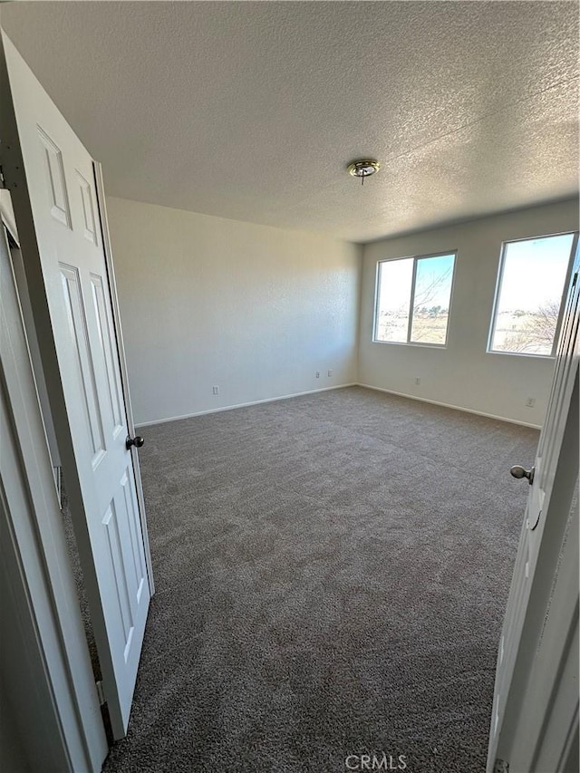 empty room with baseboards, carpet floors, and a textured ceiling