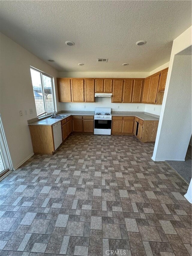 kitchen with white appliances, baseboards, visible vents, light countertops, and brown cabinets