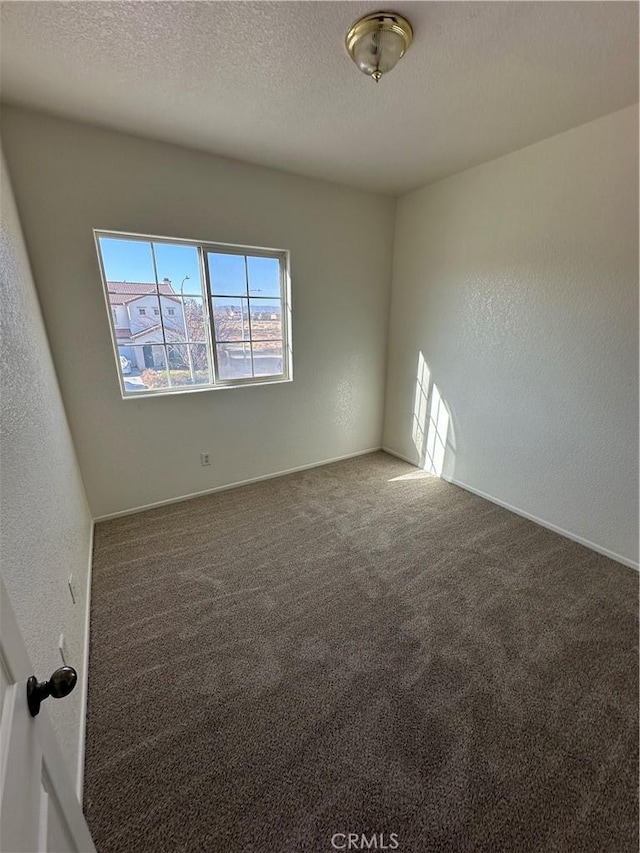 empty room featuring carpet flooring, a textured wall, and a textured ceiling