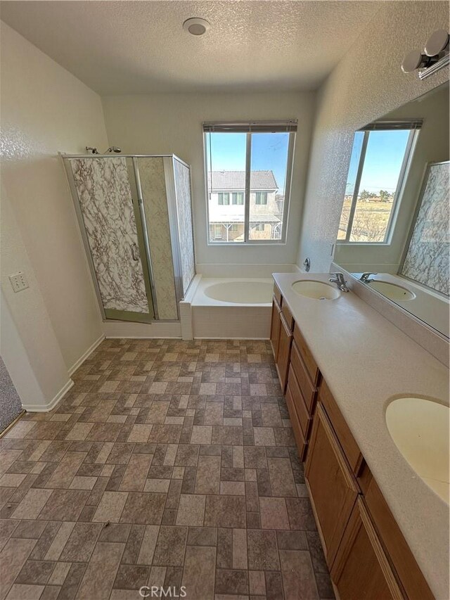 bathroom with a sink, a garden tub, a stall shower, and a textured ceiling
