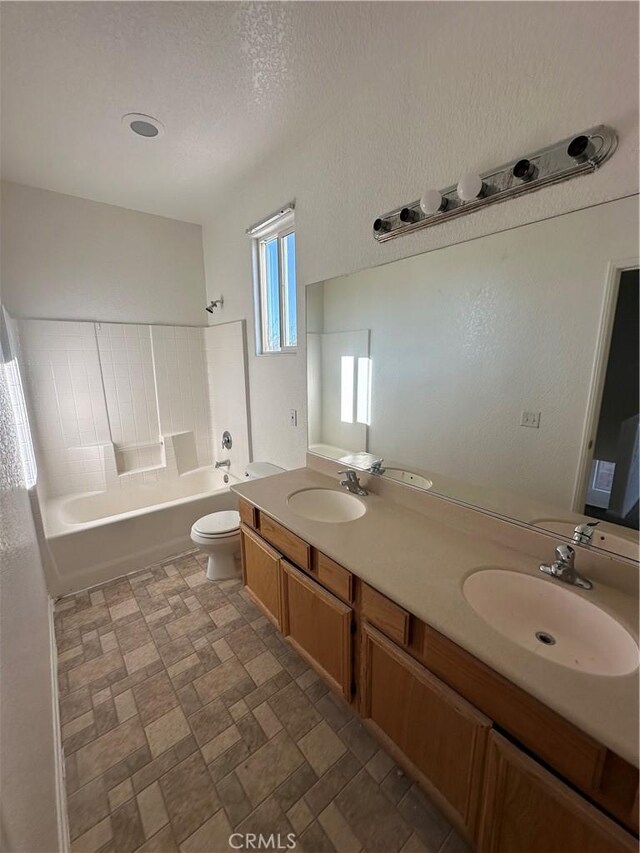 bathroom with double vanity, toilet,  shower combination, and a sink
