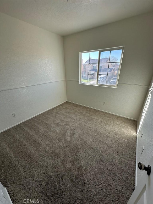 carpeted spare room featuring a textured wall and a textured ceiling