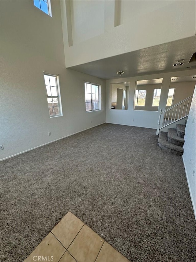 unfurnished room featuring stairway, carpet, a high ceiling, and visible vents