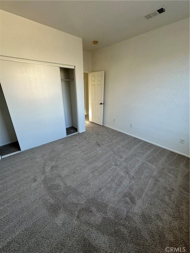 unfurnished bedroom featuring visible vents, a closet, and carpet flooring