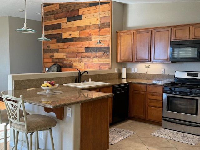 kitchen with sink, a kitchen breakfast bar, dark stone counters, light tile patterned flooring, and black appliances