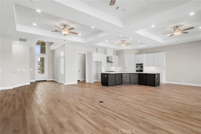 unfurnished living room with a tray ceiling, light hardwood / wood-style flooring, and sink