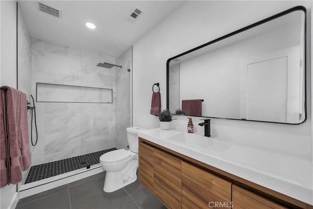 bathroom with toilet, a baseboard heating unit, tiled shower, tile patterned floors, and vanity