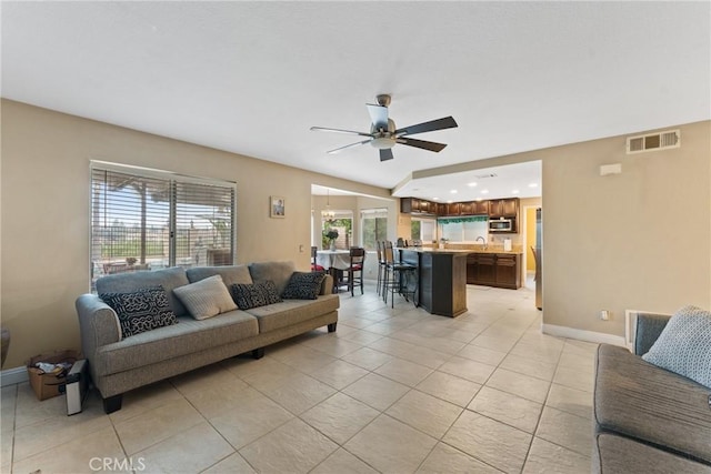 tiled living room featuring ceiling fan, lofted ceiling, and sink