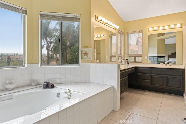 bathroom featuring tile patterned floors, tiled tub, vanity, and vaulted ceiling