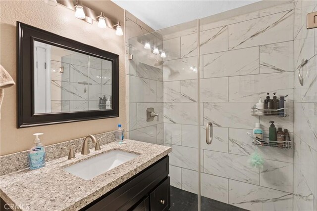 bathroom featuring a shower with door and vanity