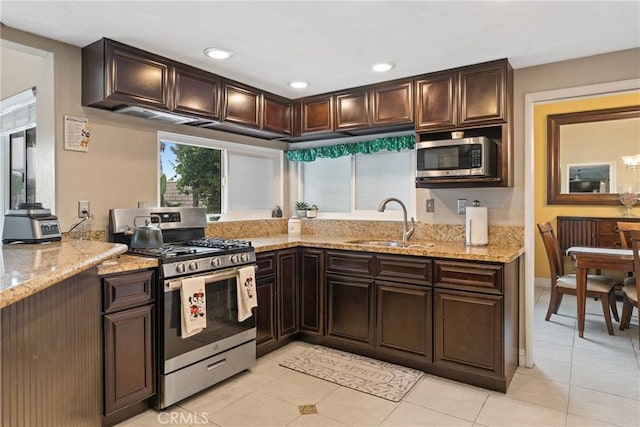 kitchen featuring light stone countertops, sink, dark brown cabinets, light tile patterned flooring, and appliances with stainless steel finishes