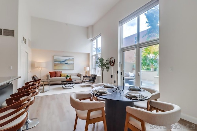 dining room featuring a towering ceiling and hardwood / wood-style flooring