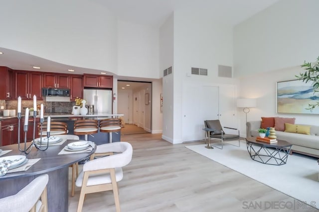 dining area with light hardwood / wood-style floors and a towering ceiling