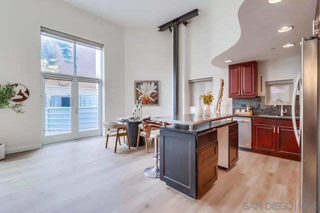 kitchen with backsplash, appliances with stainless steel finishes, sink, and light wood-type flooring