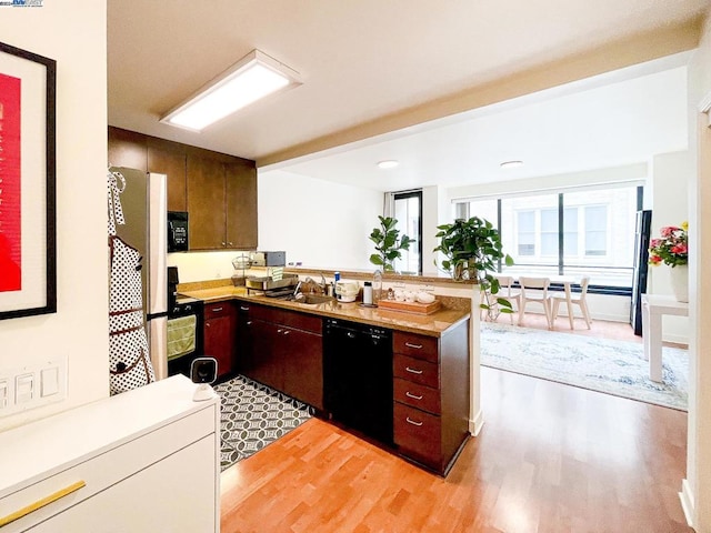 kitchen featuring sink, black appliances, light hardwood / wood-style flooring, and kitchen peninsula