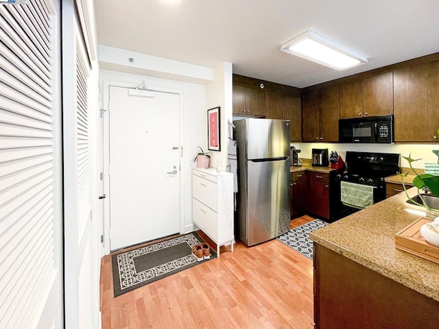 kitchen with black appliances, dark brown cabinetry, and light wood-type flooring