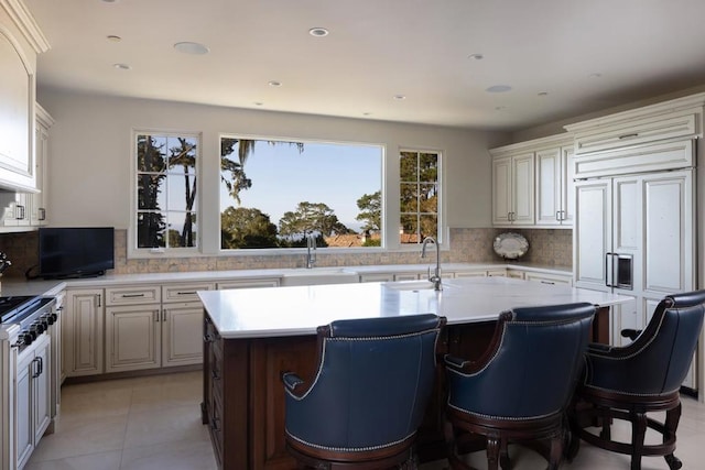 kitchen featuring light tile patterned floors, sink, an island with sink, and range