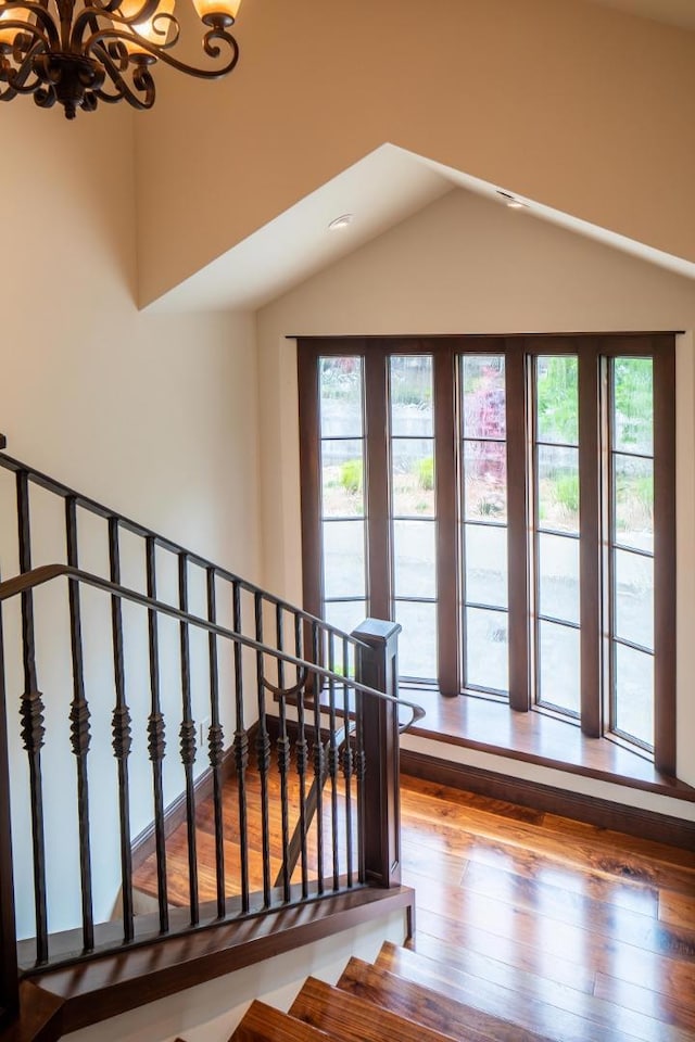 stairs with wood-type flooring, a chandelier, and a healthy amount of sunlight